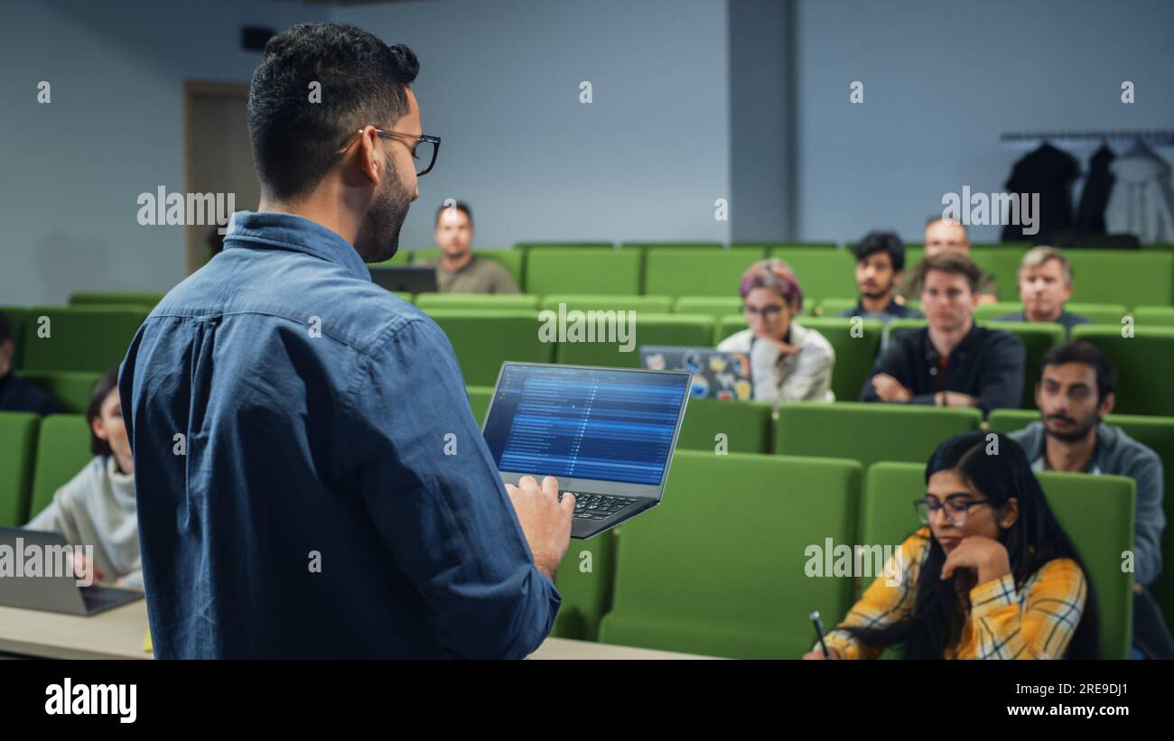 Insegnante che tiene una lezione a un gruppo multietnico eterogeneo di studenti femminili e maschili nella moderna sala del Collegio. Studiosi curiosi e premurosi che studiano Foto Stock