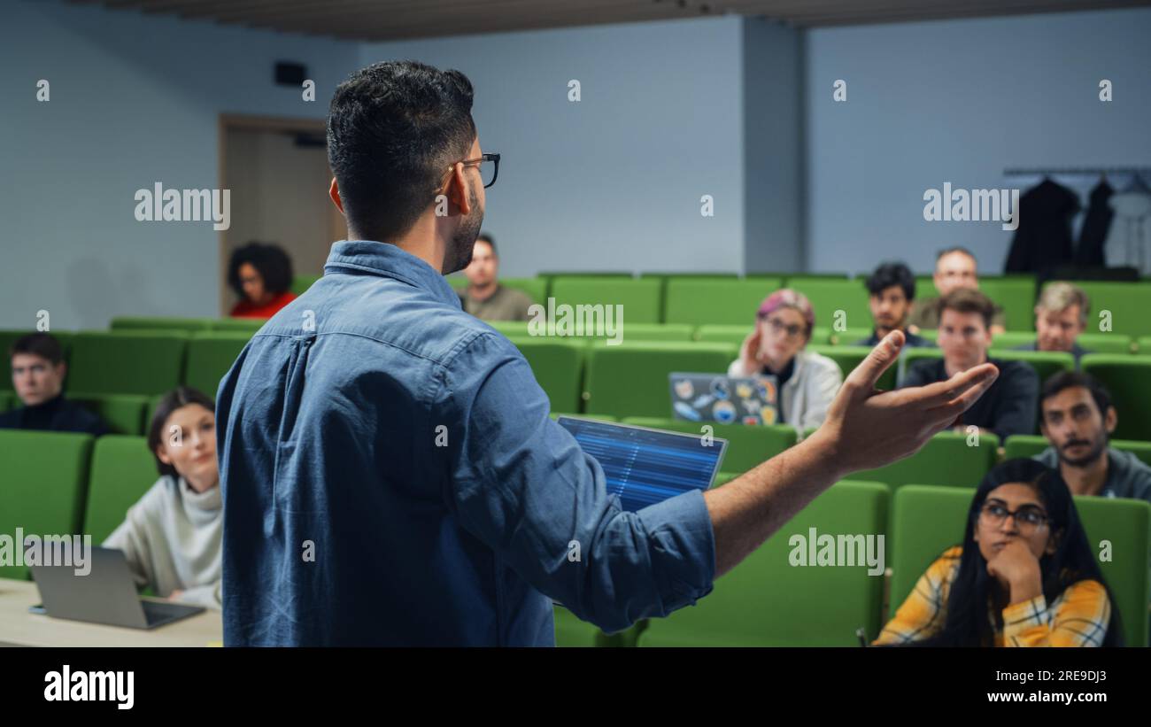 Insegnante che tiene una lezione a un gruppo multietnico eterogeneo di studenti femminili e maschili nella moderna sala del Collegio. Studiosi curiosi e premurosi che studiano Foto Stock