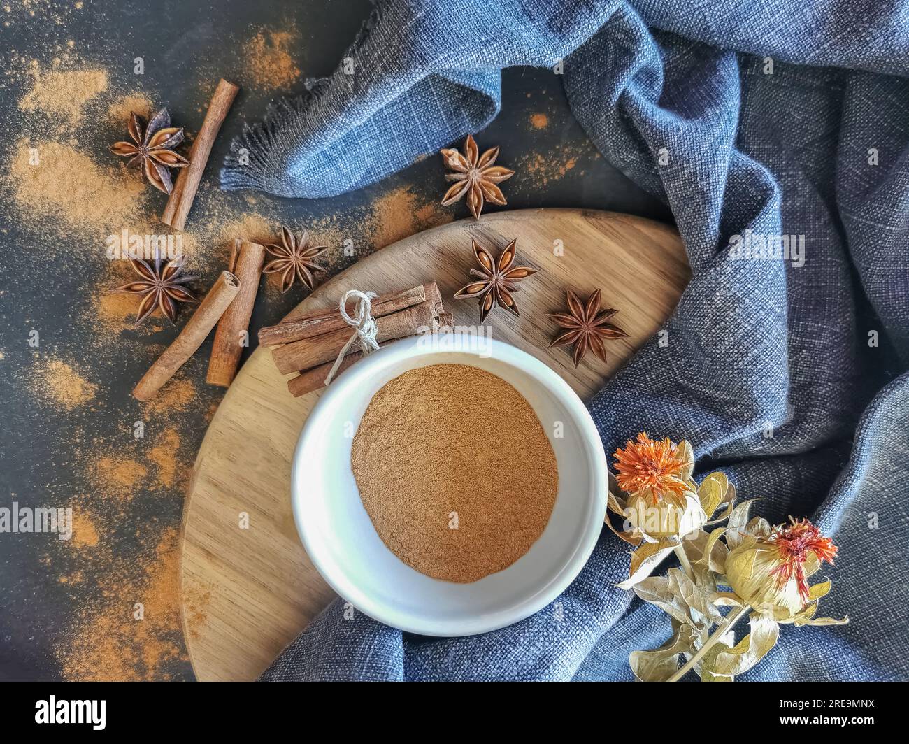 Vista sul tavolo, decorata con panini di cannella secchi e polvere di cannella all'interno di una ciotola, diversi fiori di anice secchi, stoffa rustica... Foto Stock