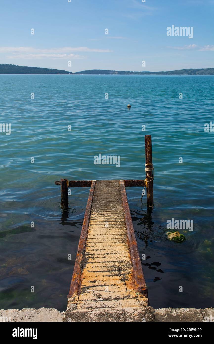 Un vecchio pontile arrugginito sulla costa adriatica della Croazia a Kastel Kambelovac a Kastela. Tarda primavera Foto Stock