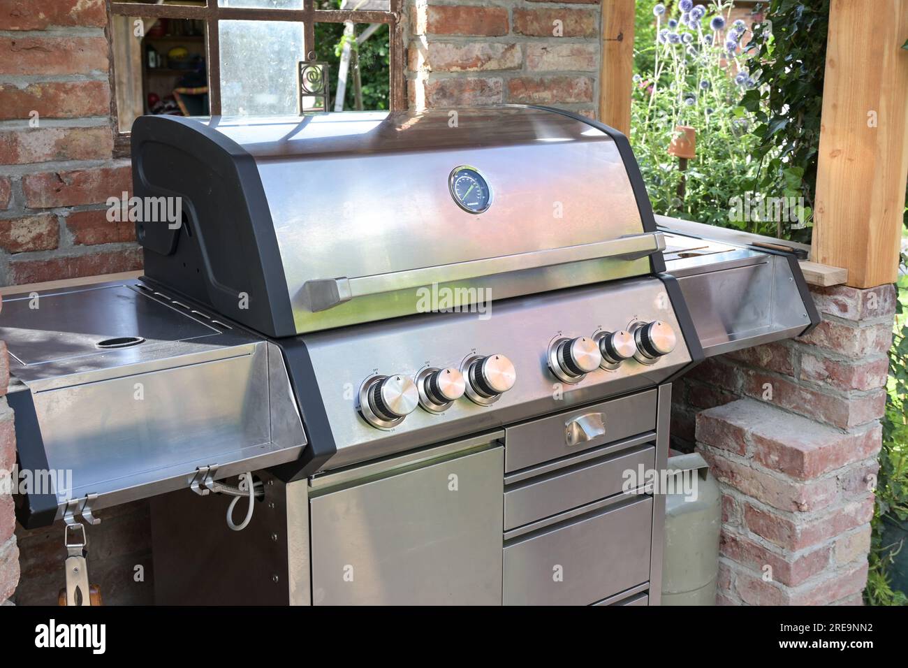 Moderna griglia per barbecue in acciaio inox in un riparo fatto di vecchi mattoni nel giardino sul retro, concetto di cucina all'aperto, messa a fuoco selezionata, zona ristretta Foto Stock
