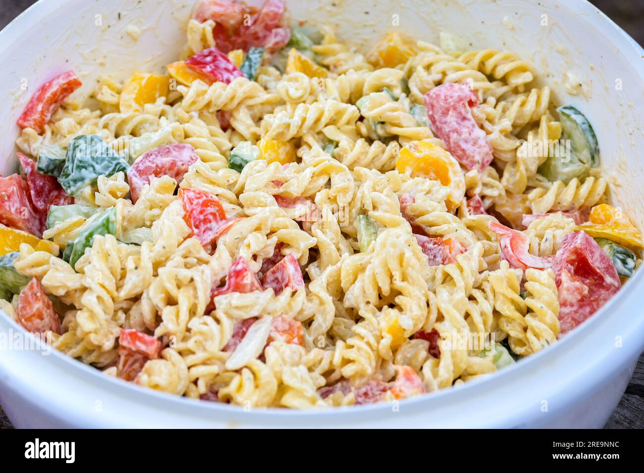 Insalata di pasta con peperoni, zucchine e maionese in un recipiente di plastica da portare con sé per una festa in giardino, messa a fuoco selezionata, profondità di campo ridotta Foto Stock