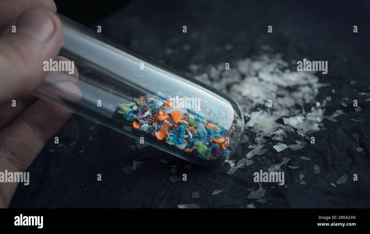 Foto macro di una provetta piena di microplastiche raccolte dalla spiaggia. Concetto di inquinamento idrico e gestione dei rifiuti industriali. Foto Stock