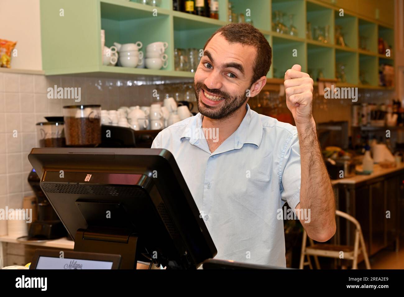 Il personale del ristorante è felice. Ritratto di un giovane uomo con barba corta che dà il pollice in alto Foto Stock