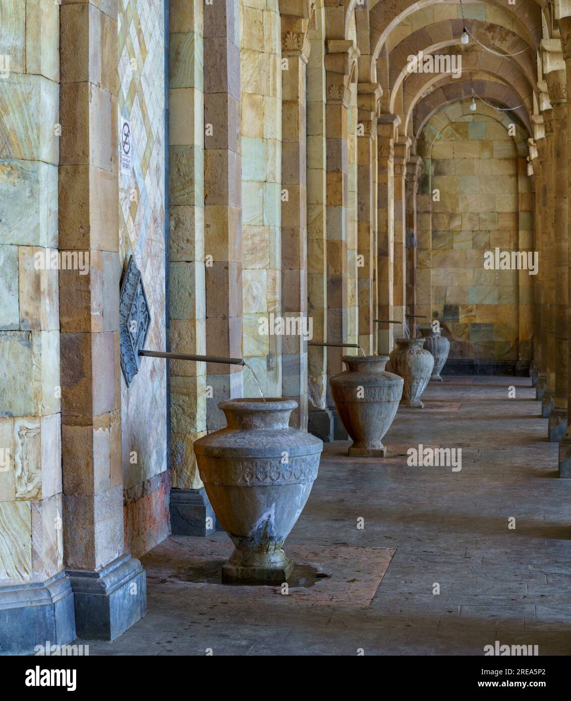 L'acqua scorre lungo un tubo sottile in una grande brocca di pietra nella galleria di acqua minerale nella località turistica di Jermuk, Armenia Foto Stock