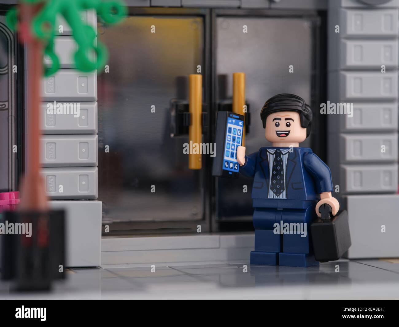 Tambov, Federazione Russa - 26 luglio 2023 Una minifigura di un uomo d'affari Lego in piedi di fronte alle porte di una banca e rispondendo al cellulare. Foto Stock