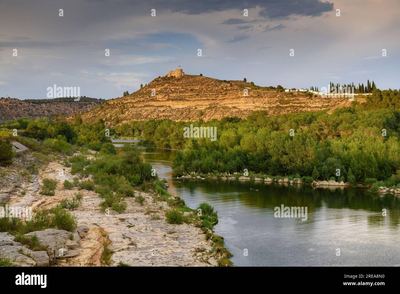 Castello di Flix sulle rive del fiume Ebro, visto dalla diga artificiale di Flix al tramonto (Ribera d'Ebre, Tarragona, Catalogna, Spagna) Foto Stock