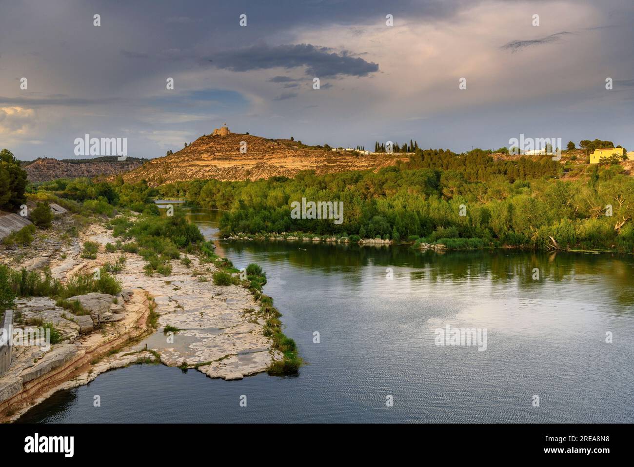 Castello di Flix sulle rive del fiume Ebro, visto dalla diga artificiale di Flix al tramonto (Ribera d'Ebre, Tarragona, Catalogna, Spagna) Foto Stock