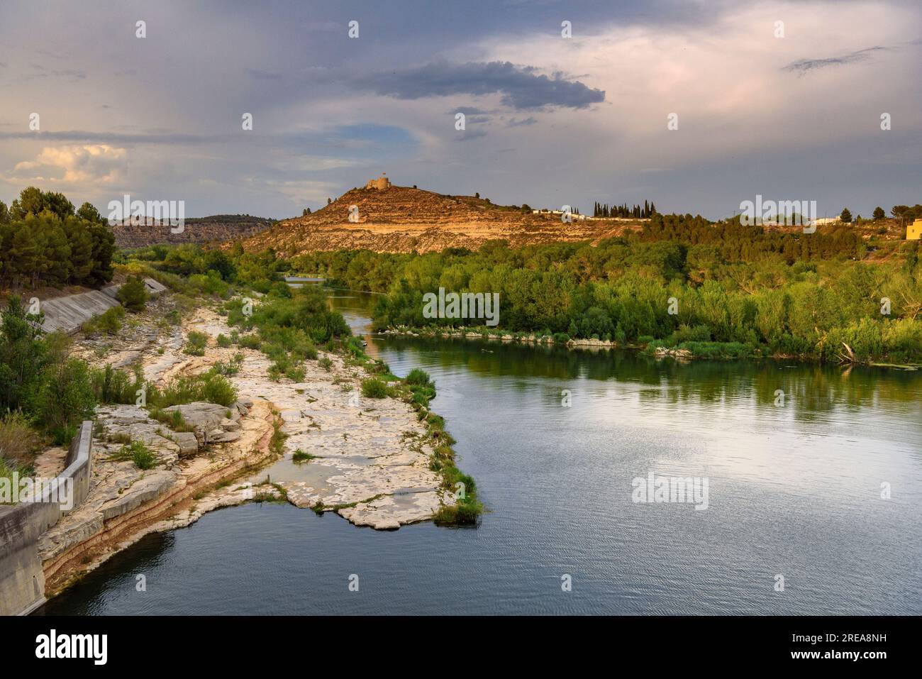 Castello di Flix sulle rive del fiume Ebro, visto dalla diga artificiale di Flix al tramonto (Ribera d'Ebre, Tarragona, Catalogna, Spagna) Foto Stock