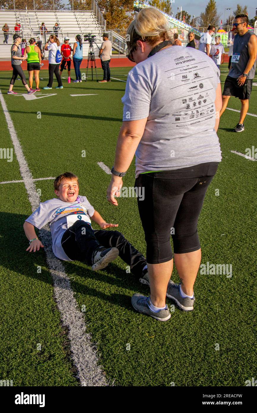 Costa Mesa, California, USA. 23 settembre 2018. Mentre sua madre tiene i piedi per forza, un bambino di 8 anni fa qualche seduta preparatoria prima di correre in una gara di calcio a Costa Mesa, CALIFORNIA. (Immagine di credito: © Spencer Grant/ZUMA Press Wire) SOLO USO EDITORIALE! Non per USO commerciale! Foto Stock