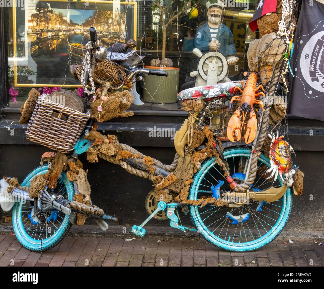 Bicicletta nautica decorata con diversi molluschi e decorazioni marine all'esterno di un negozio di pesce ad Amsterdam Foto Stock