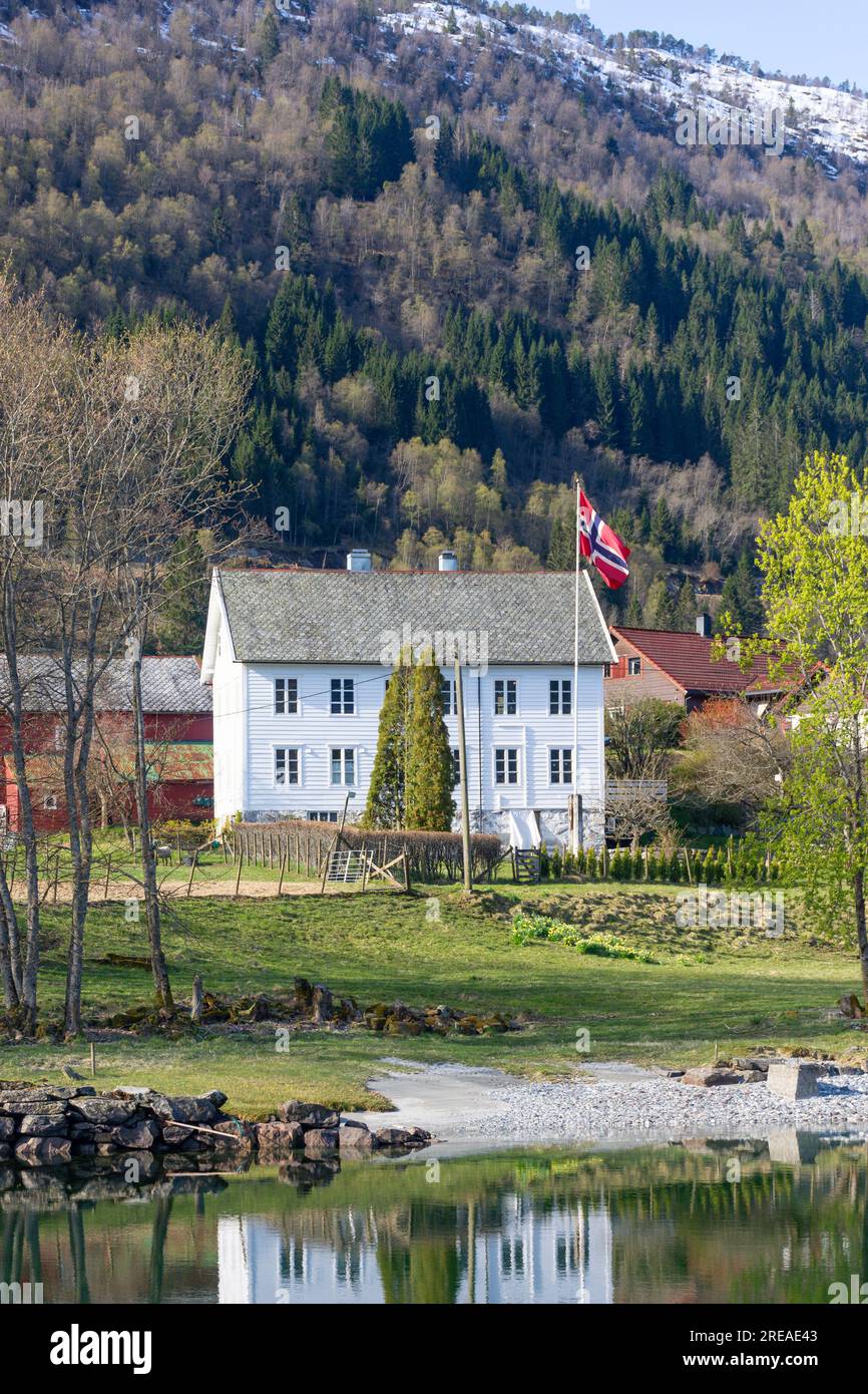 Casa di legno con bandiera norvegese sul fiume Eid (Eidselva), Nordfjordeid, Vestland County, Norvegia Foto Stock