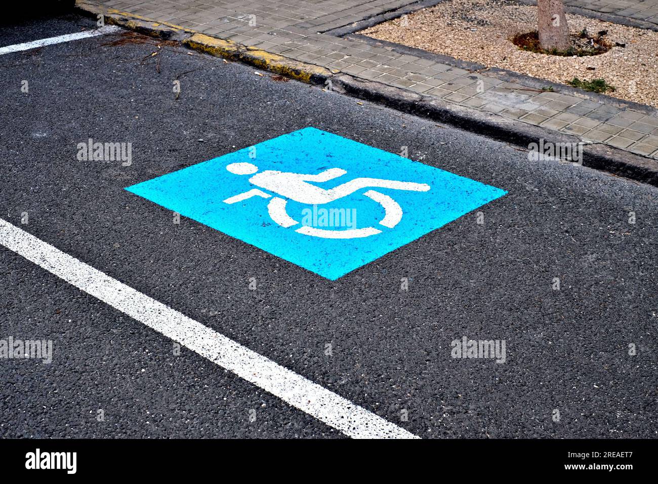 Simbolo blu della sedia a rotelle che indica un parcheggio riservato ai conducenti con disabilità fisiche. Foto Stock