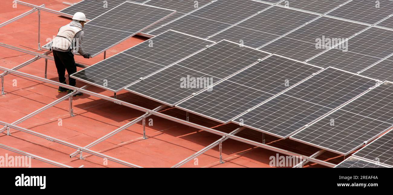 Lavoratore che installa pannelli solari sulla terrazza del tetto Foto Stock