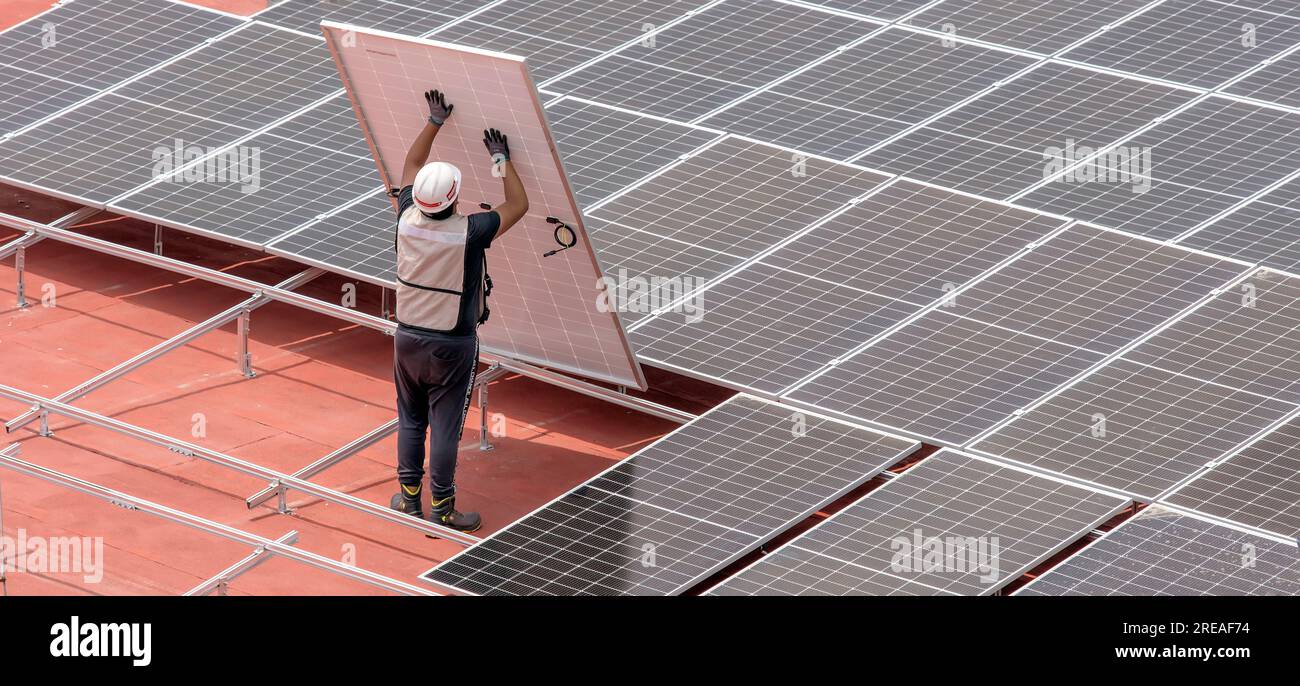 Lavoratore che installa pannelli solari sulla terrazza del tetto Foto Stock