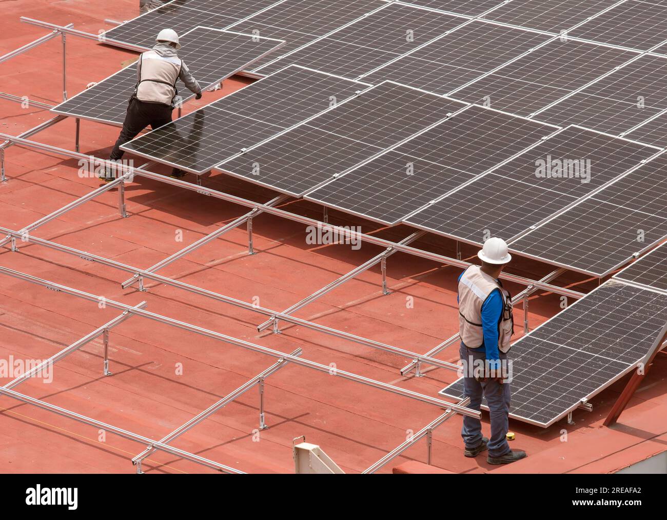 Lavoratori che installano pannelli solari sulla terrazza del tetto Foto Stock