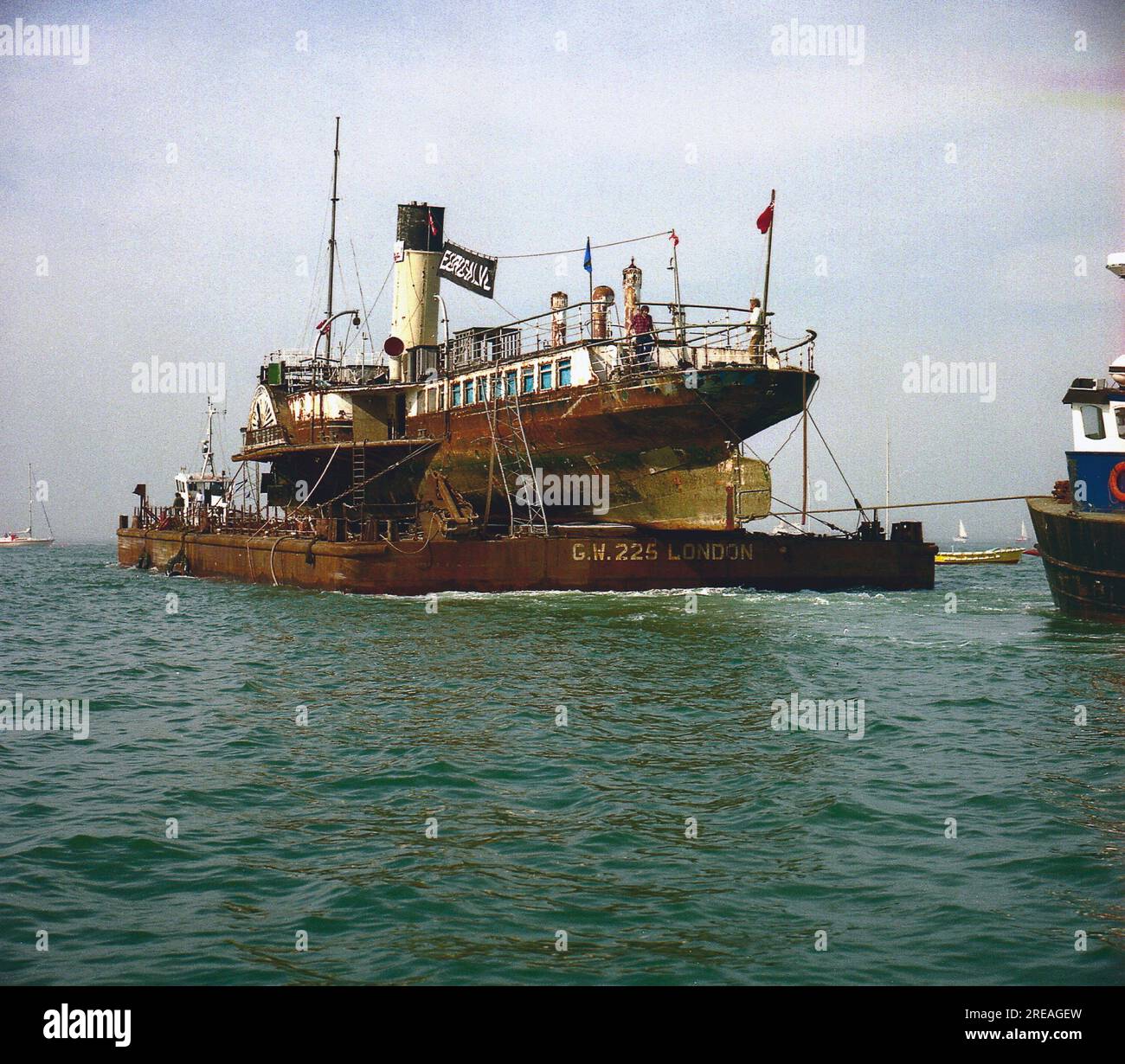 AJAXNETPHOTO. 20 APRILE 1984. COWES, ISOLA DI WIGHT, INGHILTERRA. - LA REGINA PRENDE UN ASCENSORE - IL PIROSCAFO MEDWAY QUEEN CARICATO SU UN PONTONE, TRAINATO FUORI DAL FIUME MEDINA IN DIREZIONE DEL TAMIGI.FOTO:JONATHAN EASTLAND/AJAX RIF:1984 4 10 Foto Stock