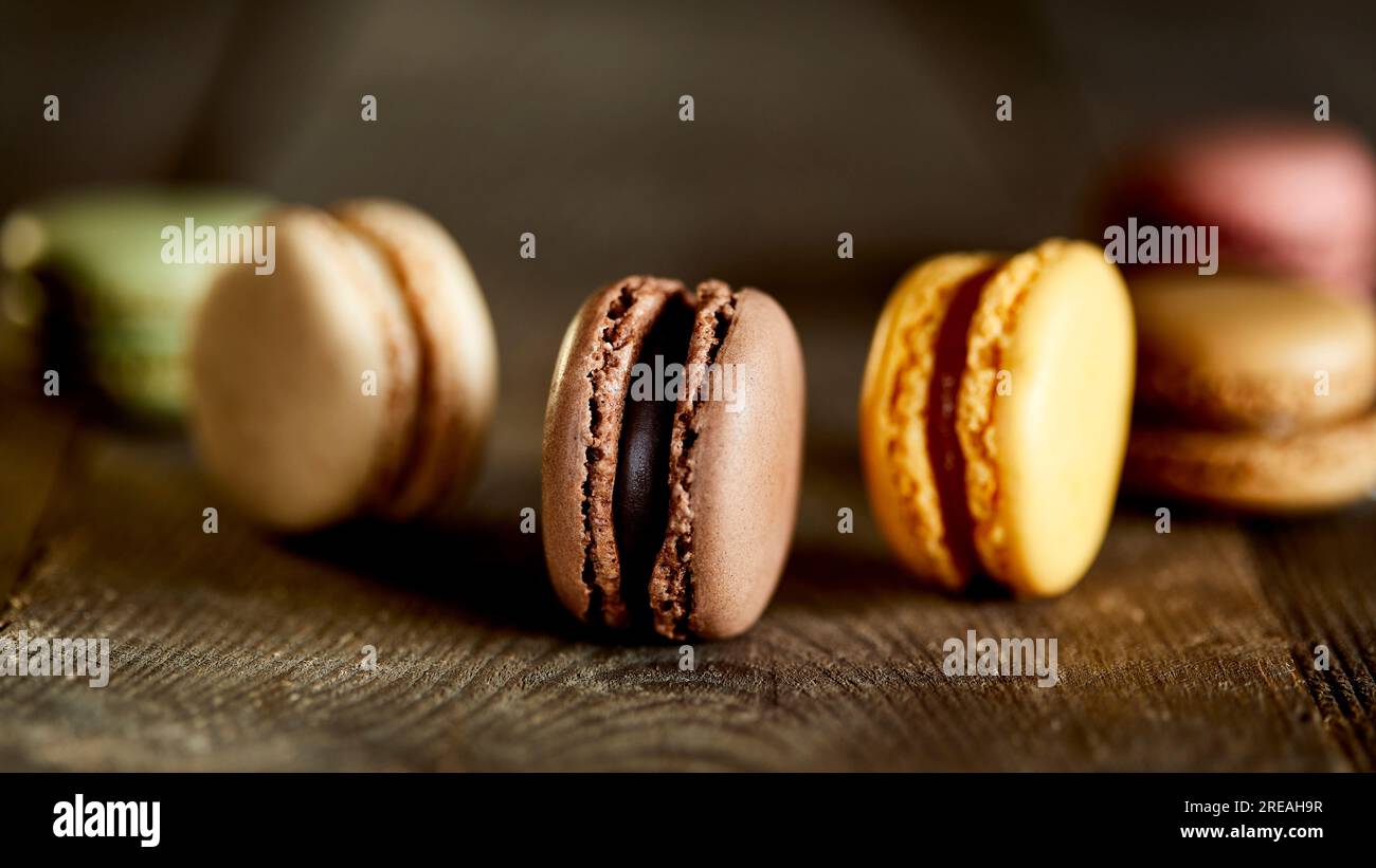 Macaron in vari gusti su superficie ruvida di legno. Foto Stock