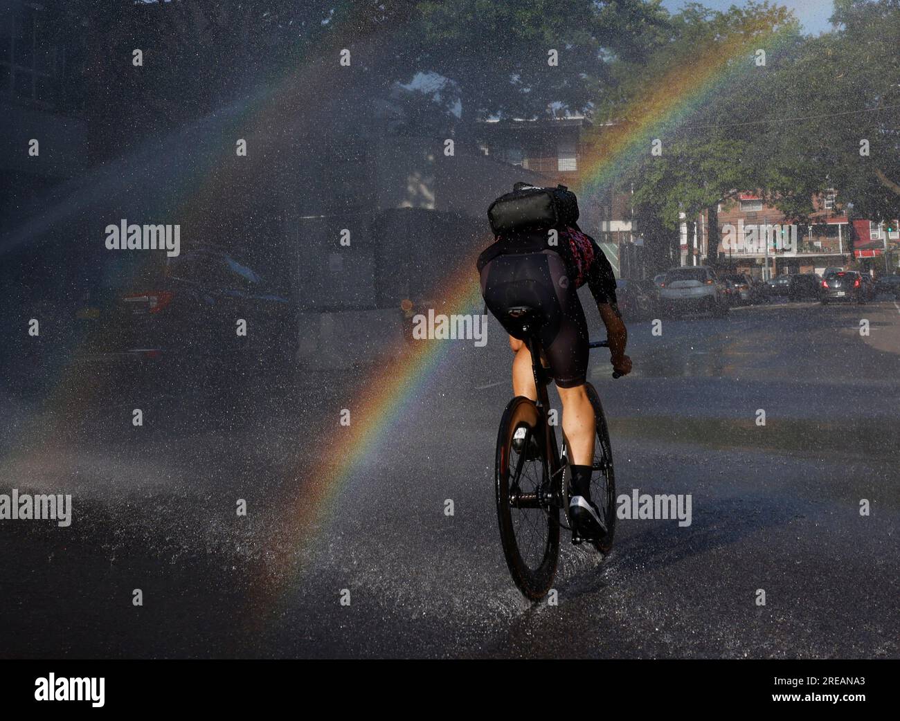 New York, Stati Uniti. 26 luglio 2023. Un ciclista pedala attraverso le acque spruzzate da un idrante di fuoco aperto mentre il caldo pericoloso si avvicina nel quartiere Queens di New York City mercoledì 26 luglio 2023. New York City e l'area metropolitana potrebbero essere circondati da temperature pericolosamente alte per diversi giorni. Foto di John Angelillo/UPI Credit: UPI/Alamy Live News Foto Stock