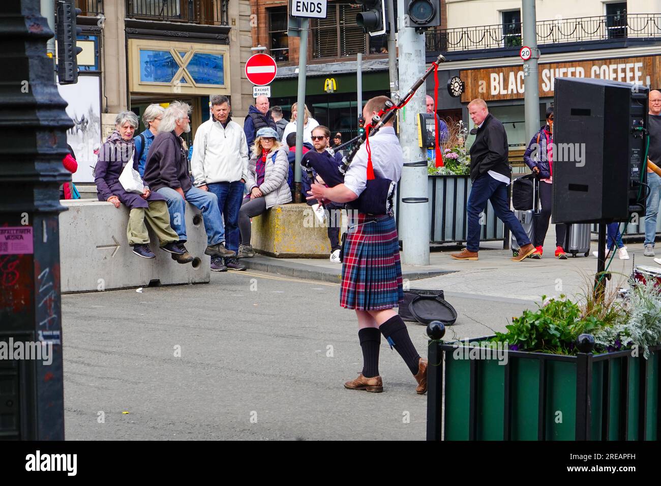 Gente che guarda piper con cornamuse su Princes Street vicino alla stazione ferroviaria di Waverley, New Town, Edimburgo, Scozia, Regno Unito. Foto Stock