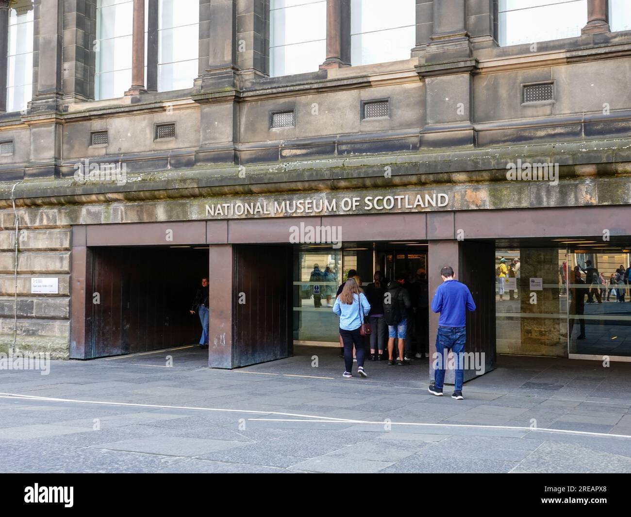 Persone fuori dal National Museum of Scotland, museo gratuito con mostre storiche e culturali, situato in Chambers St, Edimburgo, Scozia, Regno Unito. Foto Stock