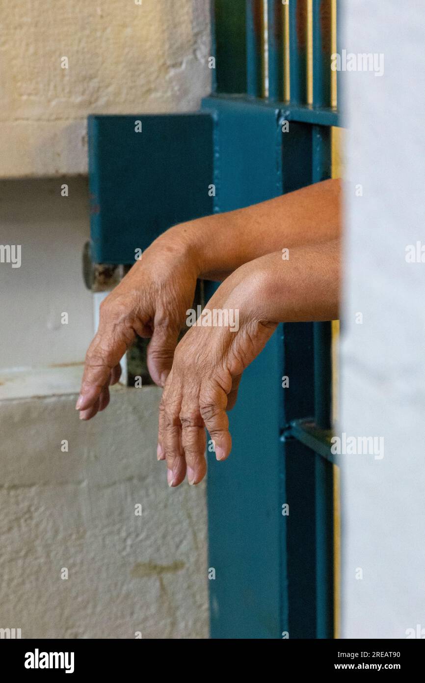 Mani che escono attraverso le sbarre della prigione. Foto Stock