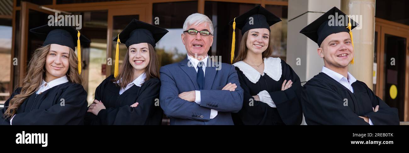 Un professore e i suoi studenti in abiti di laurea con le braccia incrociate sulle loro casse. Foto Stock