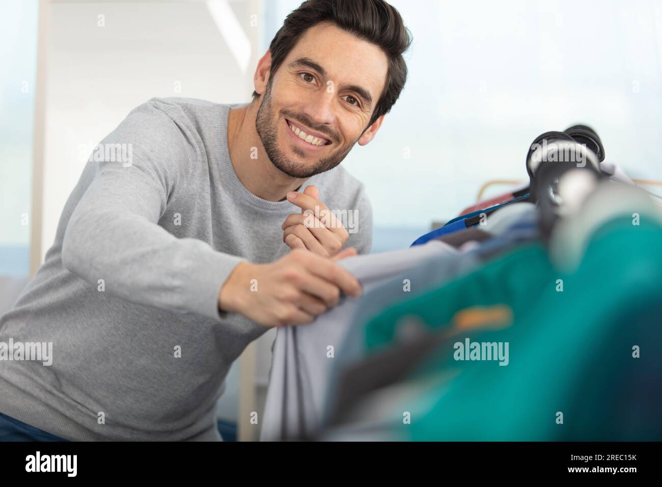 bel giovane uomo che sceglie la giacca nel suo guardaroba Foto Stock