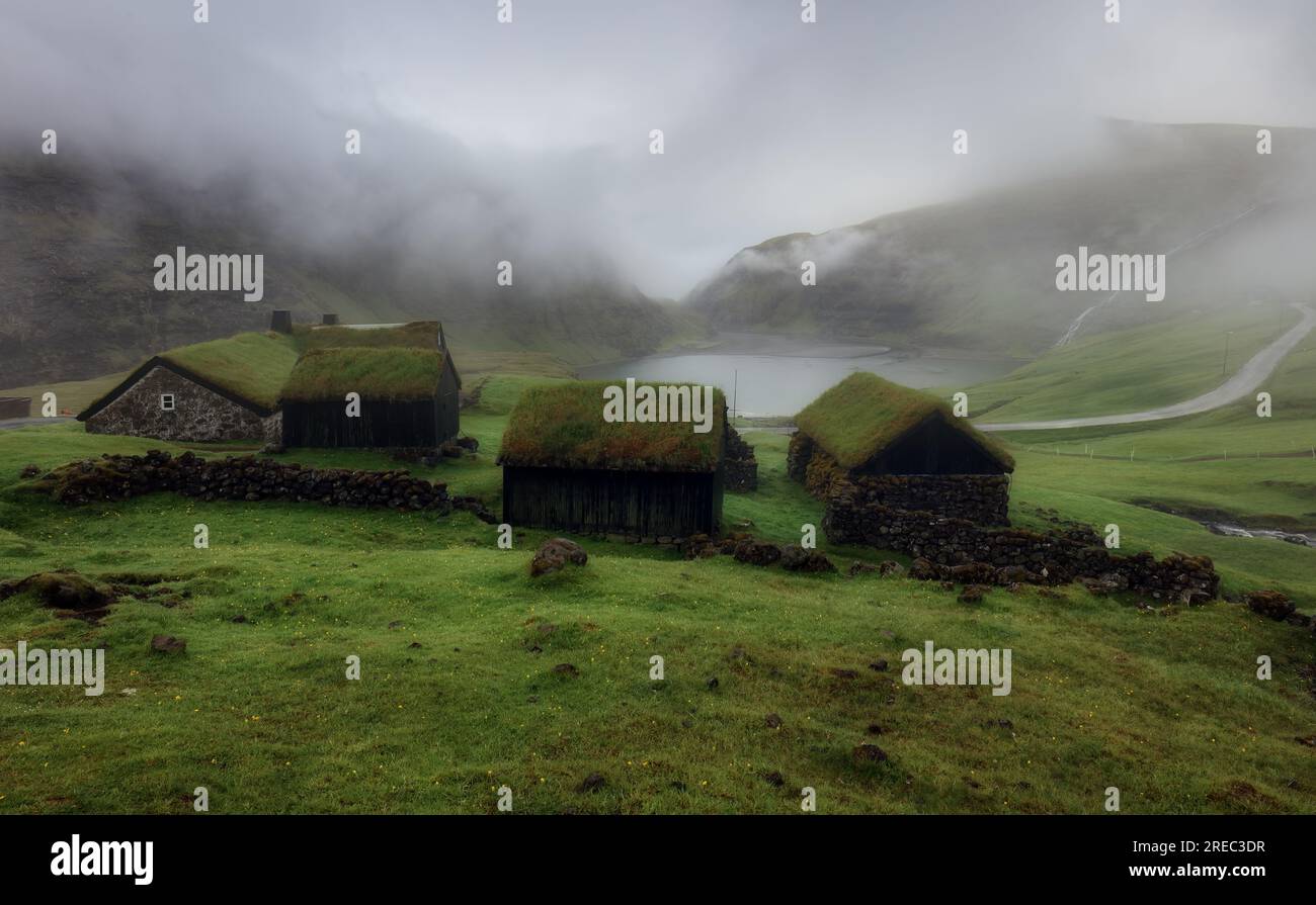 Isole Faroe - case sul tetto in erba nel piccolo villaggio Saksun, atmosfera nuvolosa Foto Stock