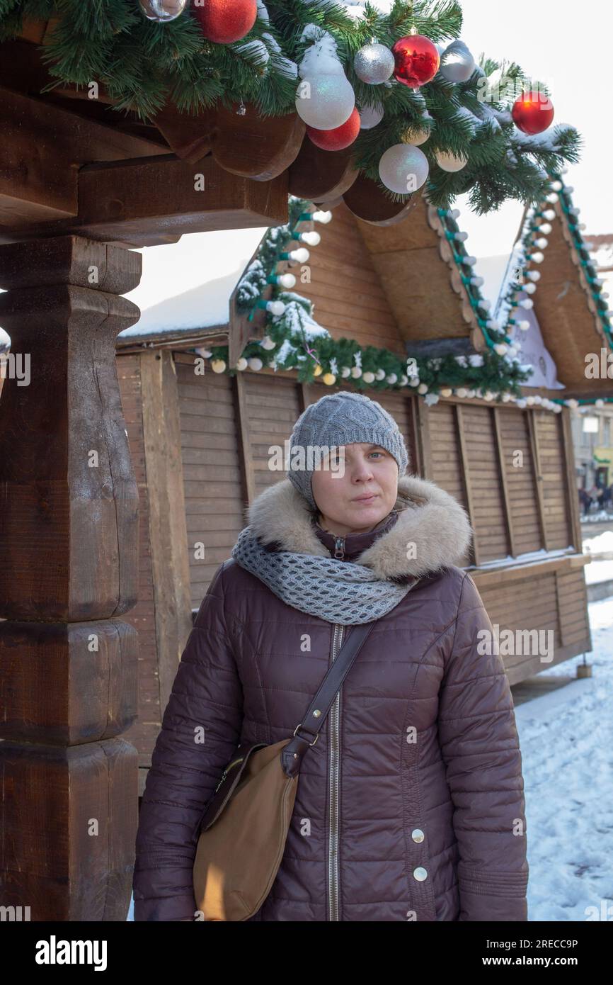donna in piedi alla fiera in inverno in una giacca lunga marrone Foto Stock