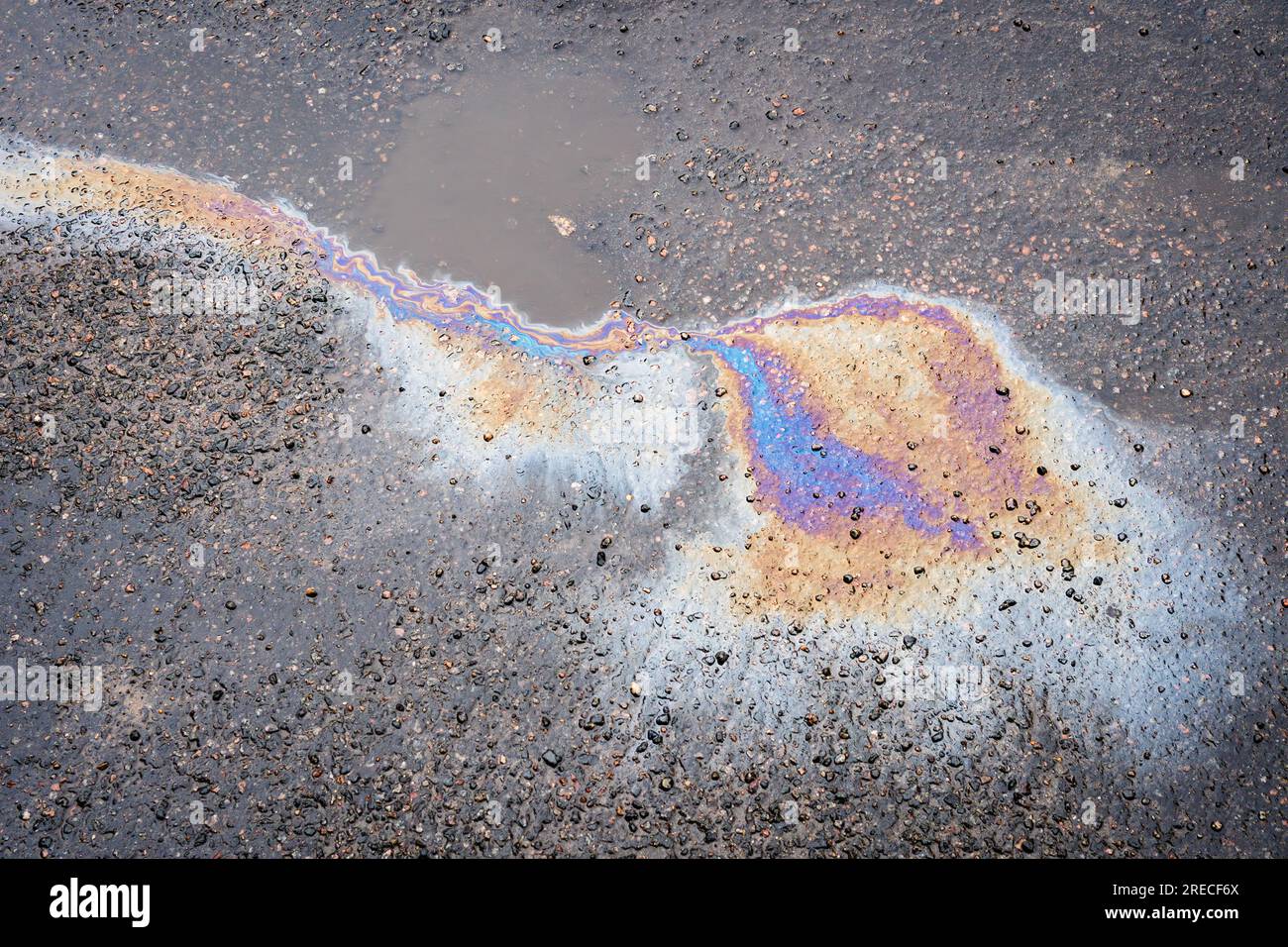Versamento di olio in una pozzanghera sulla strada. Macchie d'olio sulla pavimentazione bagnata. Foto Stock