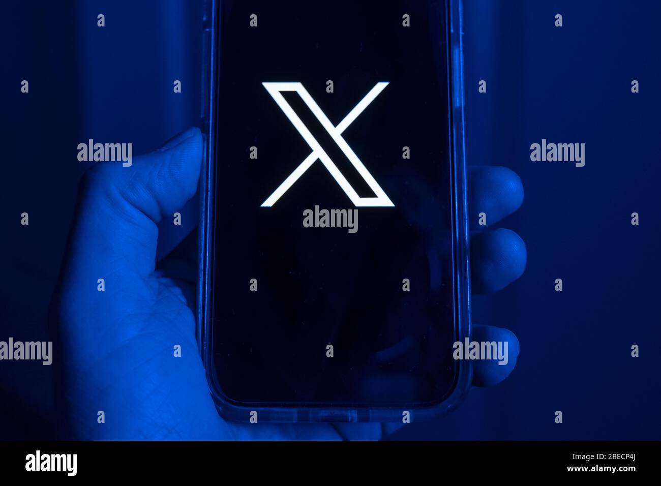 Telefono cellulare in una mano con il simbolo X, il nuovo nome della precedente app Twitter Foto Stock
