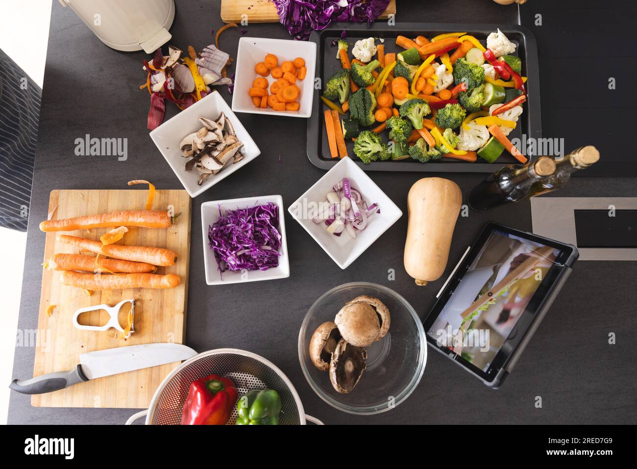 Verdure fresche in ciotole e tablet con video di cottura sullo schermo sul bancone della cucina a casa Foto Stock