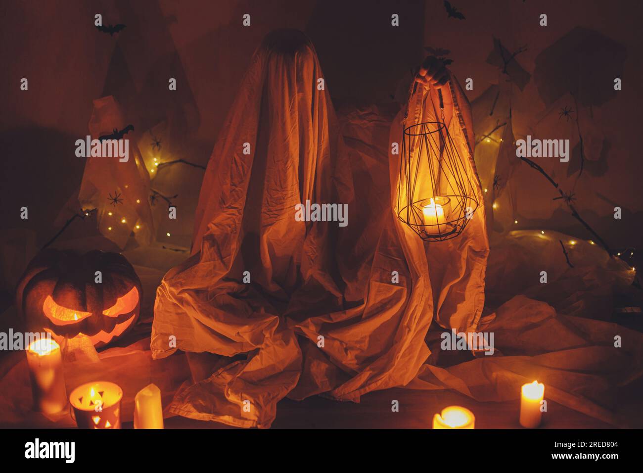Fantasma spaventoso che tiene la lanterna al buio. Decorazioni spaventose di halloween e persona vestita da fantasma con zucca luminosa. Buon Halloween! Trucco Foto Stock