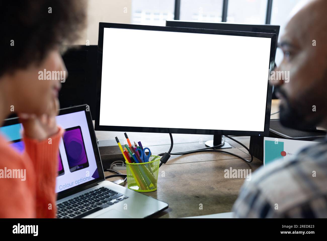 Vista posteriore di diversi designer maschili e femminili che discutono al computer con spazio per la copia in ufficio Foto Stock