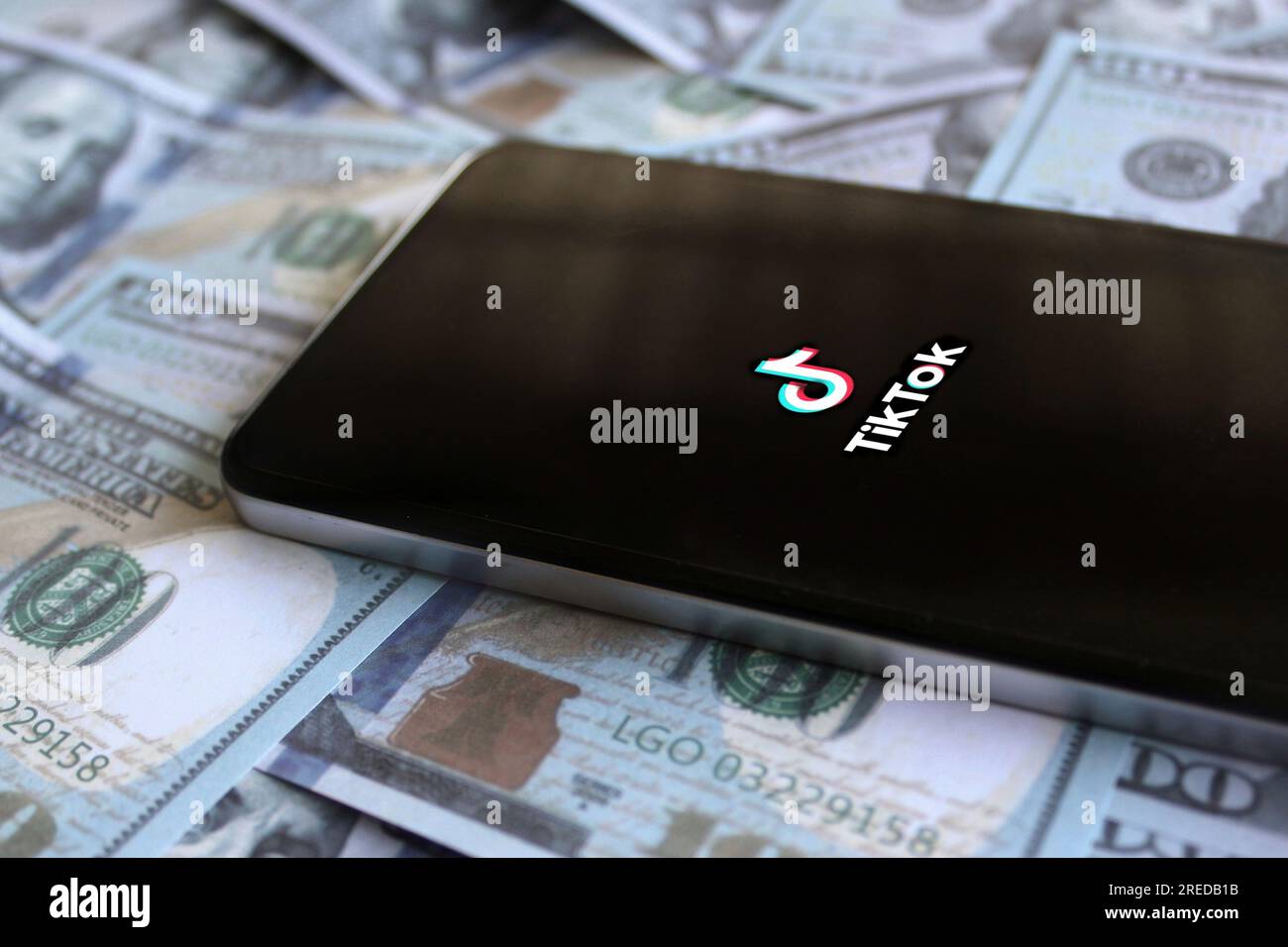 Logo dell'app TikTok su smartphone e denaro. Concetto di fatturato, business e profitto Foto Stock