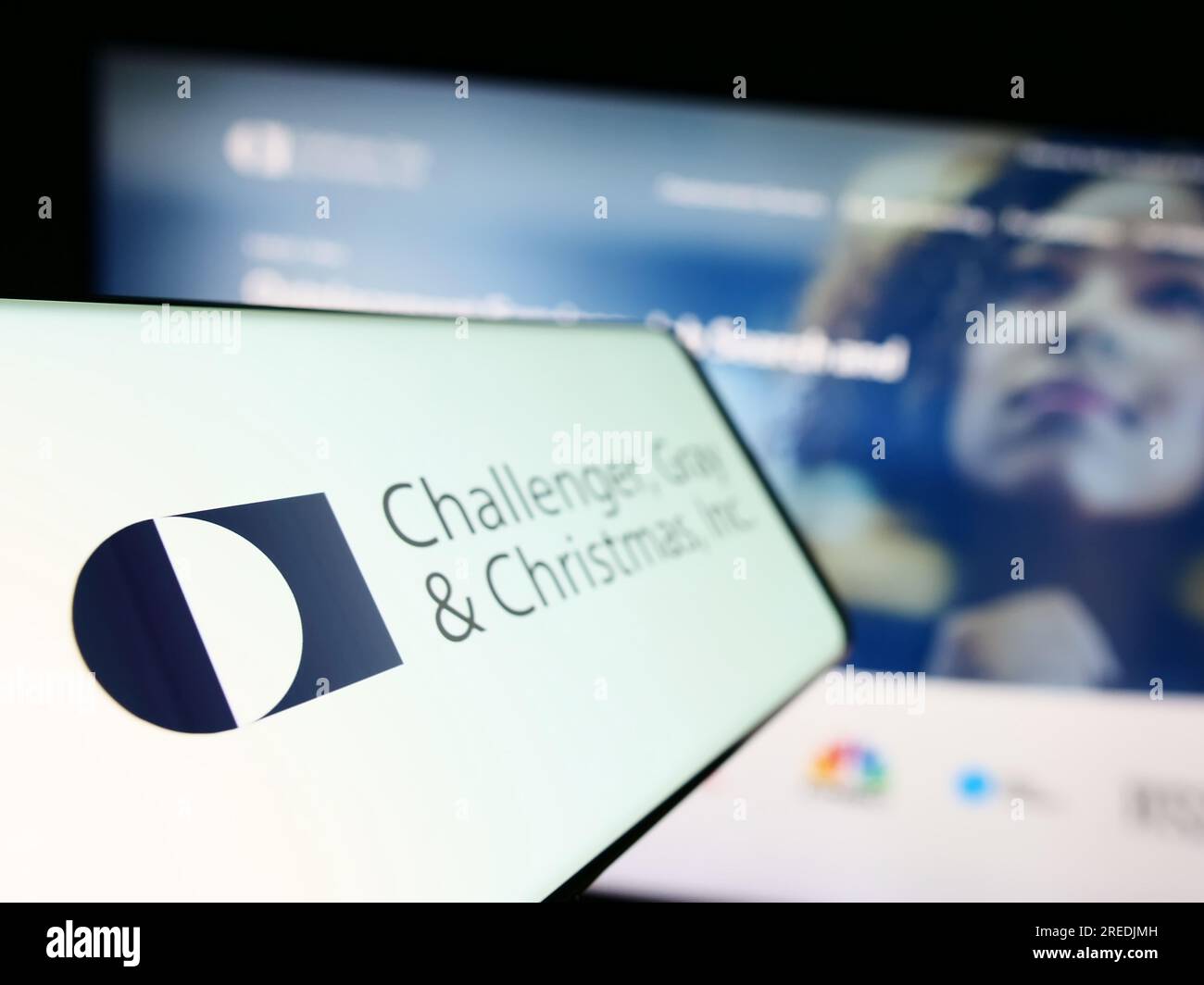 Telefono cellulare con logo dell'azienda americana Challenger, Gray and Christmas Inc. Sullo schermo davanti al sito Web. Mettere a fuoco sul lato sinistro del display del telefono. Foto Stock