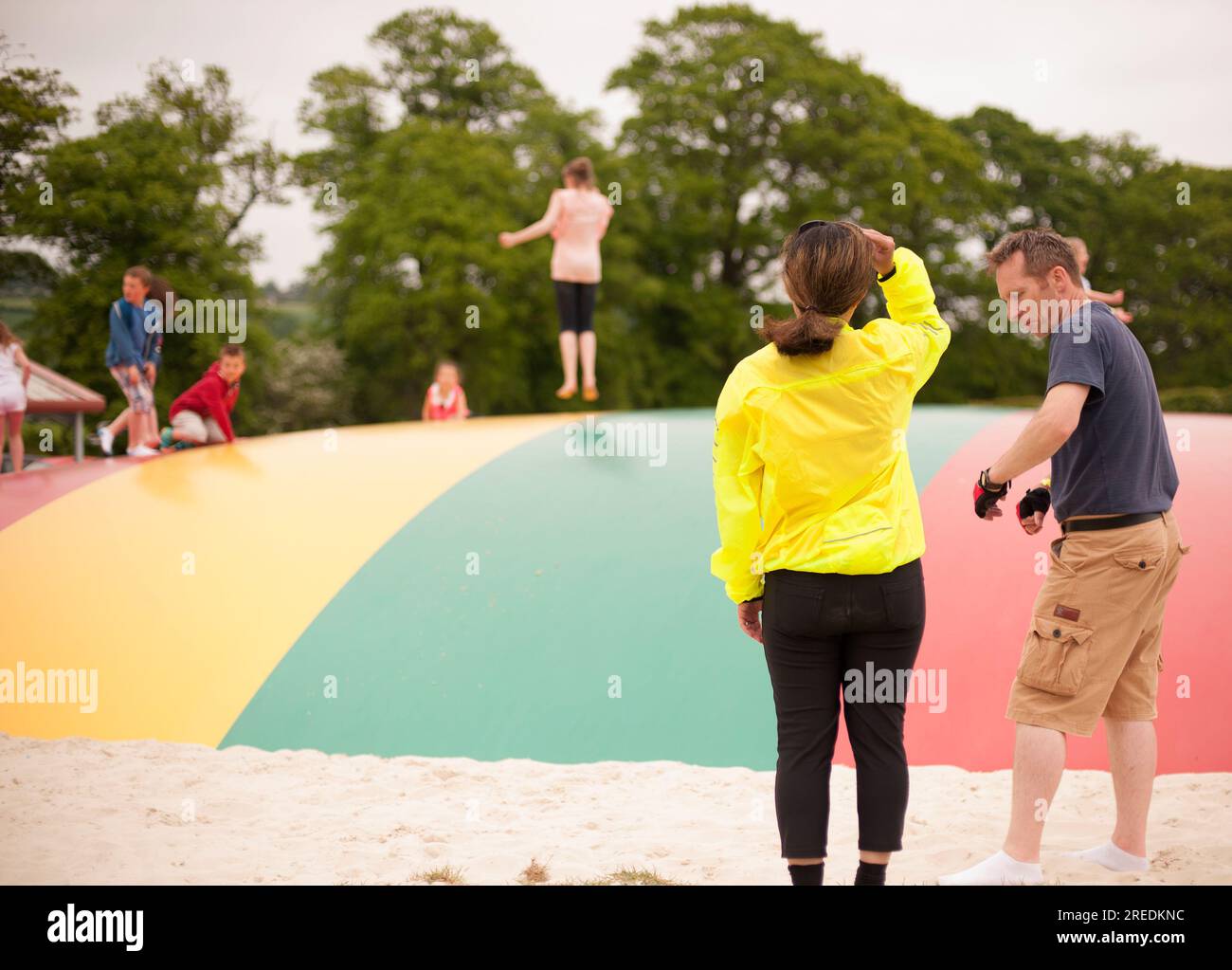 I genitori guardano mentre i bambini saltano su un grande trampolino a Briarlands Farm, a conduzione familiare per bambini e adulti, a Blair Drummond, Stirling, Scozia Foto Stock