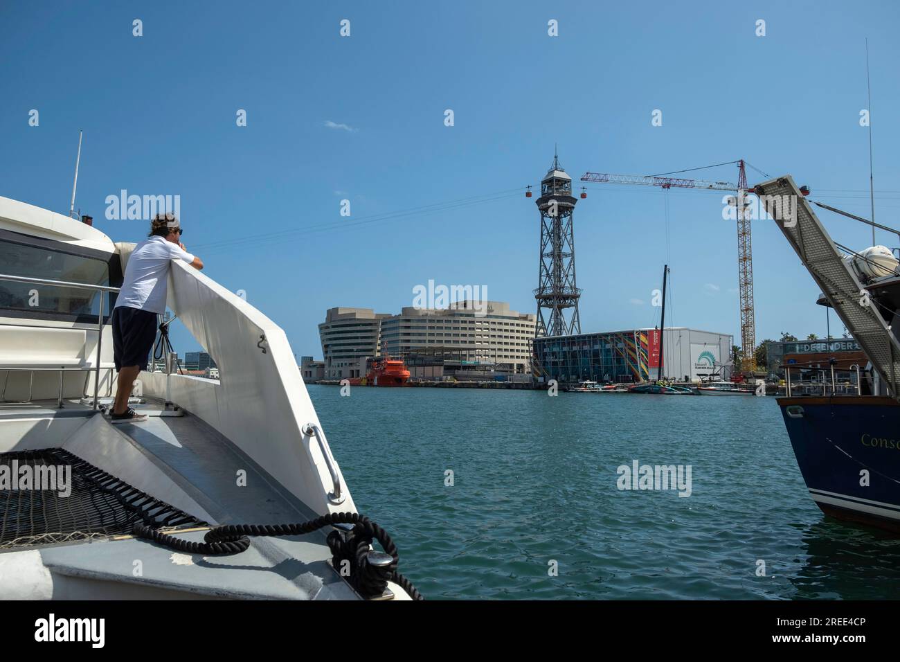 Barcellona, Spagna. 26 luglio 2023. Un uomo guarda da una barca l'attività nel padiglione Emirates Team New Zealand. Le strutture della competizione velica American's Cup Barcelona iniziano ad essere visibili nel porto di Barcellona. Alcune delle basi nautiche delle squadre che parteciperanno alle più importanti competizioni sportive veliche mostrano già le bandiere dei loro paesi. Alcune squadre si allenano già nelle acque del porto di Barcellona. Credito: SOPA Images Limited/Alamy Live News Foto Stock