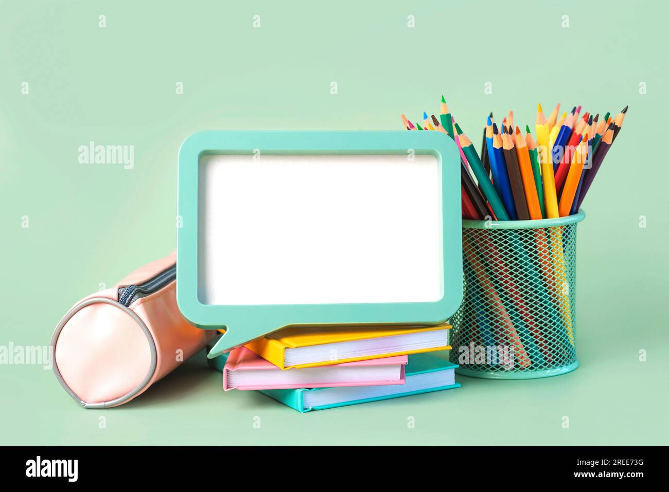 Astuccio, quaderni, matite colorate in vasetto e cornice con spazio per testo su sfondo verde. Concetto di ritorno a scuola Foto Stock