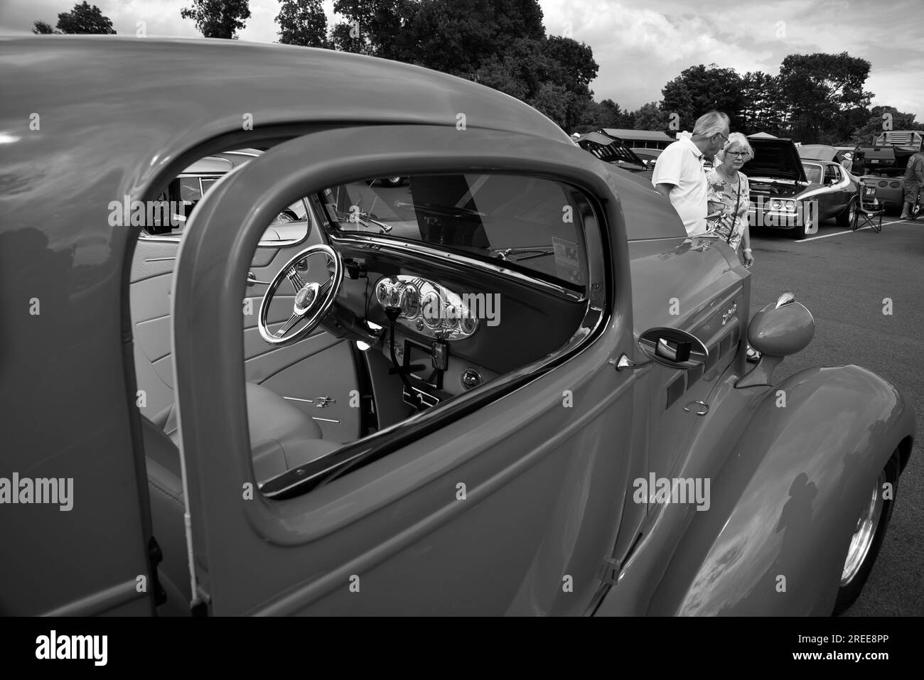 I visitatori di una mostra di auto d'epoca e personalizzate americane passeranno davanti a un'automobile Packard personalizzata del 1937 Foto Stock
