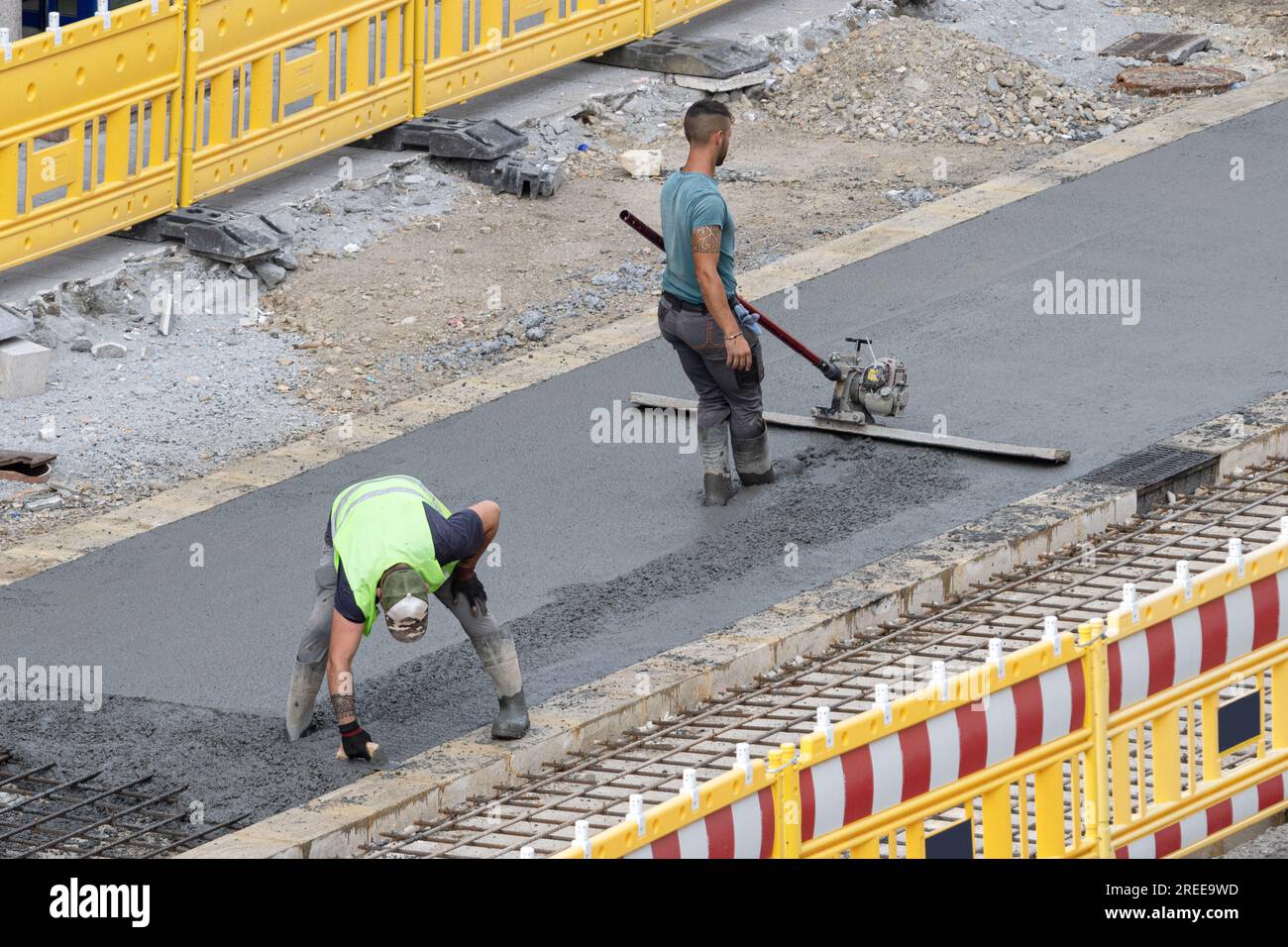 Galizia, Spagna; 20 luglio 2023: Lavoratori che lavorano su una strada urbana per la lucidatura del calcestruzzo in un cantiere Foto Stock