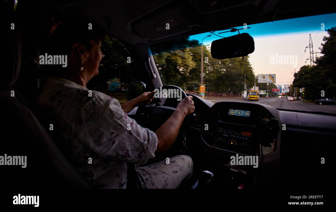 Donna adulta matura sorridente mentre guida un'auto Foto Stock
