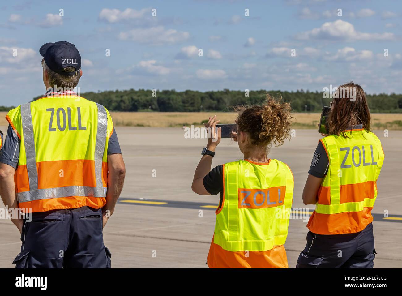 Funzionari doganali che indossano gilet ad alta visibilità, grembiule dell'aeroporto di Schoenefeld, Brandeburgo, Germania Foto Stock