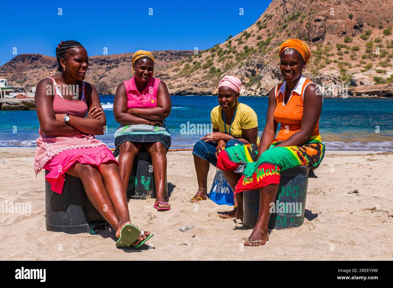 Donne dalla pelle scura, sedute a spiaggia di sabbia e che parlano tra loro. Tarrafal. Santiago. Cabo Verde. Africa Foto Stock
