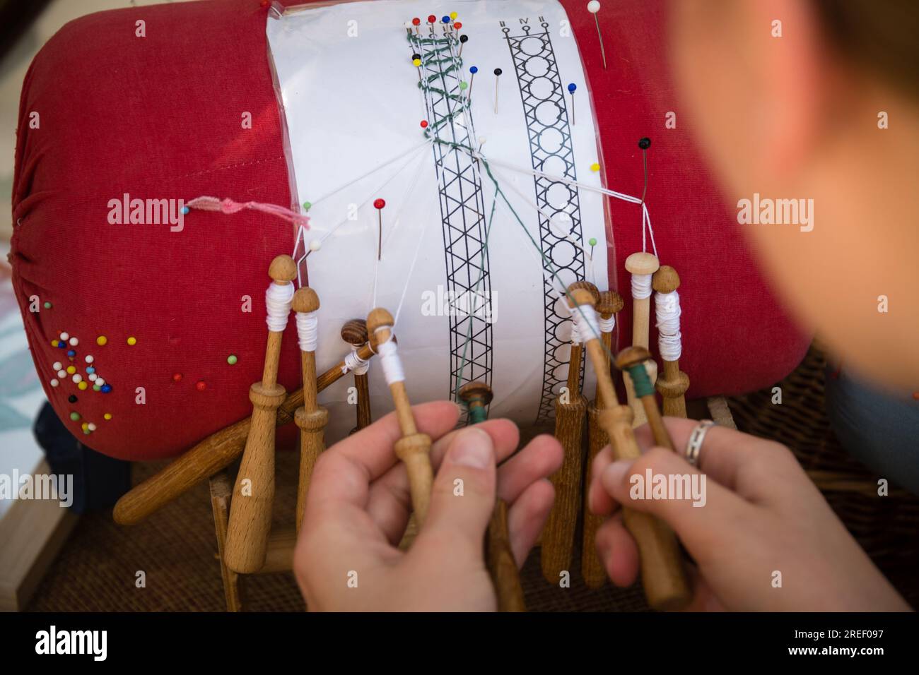 Le mani di artigiani che fanno il merletto con le bobine - arte popolare Foto Stock