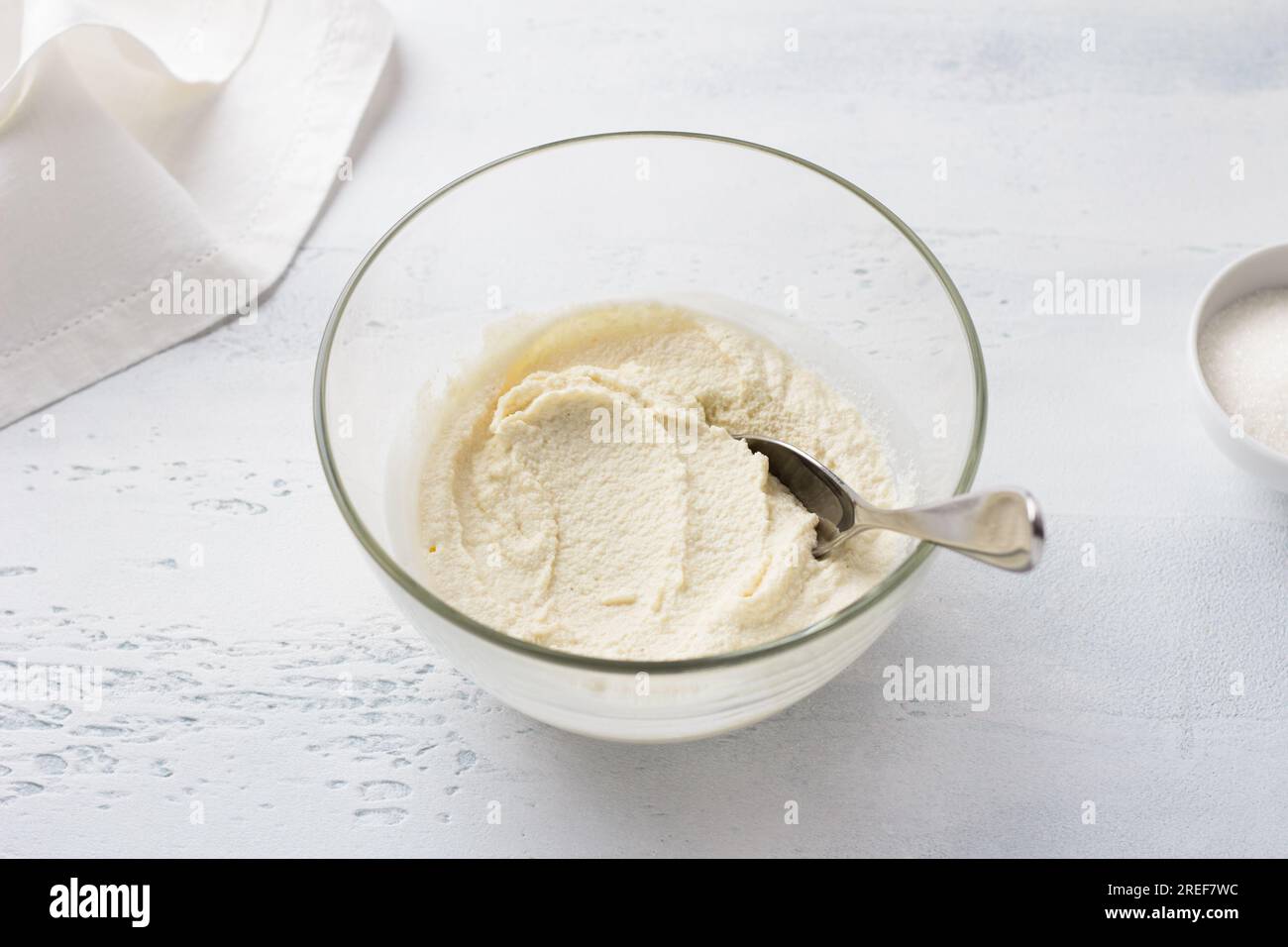 Ciotola di vetro con semola imbevuta, mannik da cucina, torta, torta su sfondo azzurro. passo dopo passo, fase di cottura. Foto Stock
