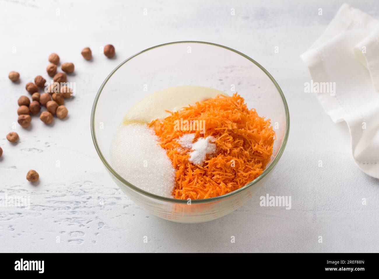 Recipiente di vetro con semola, uova, carote grattugiate, zucchero, sale e lievito in polvere. cucinare mannik, torta o torta su sfondo azzurro. passo dopo passo, c Foto Stock