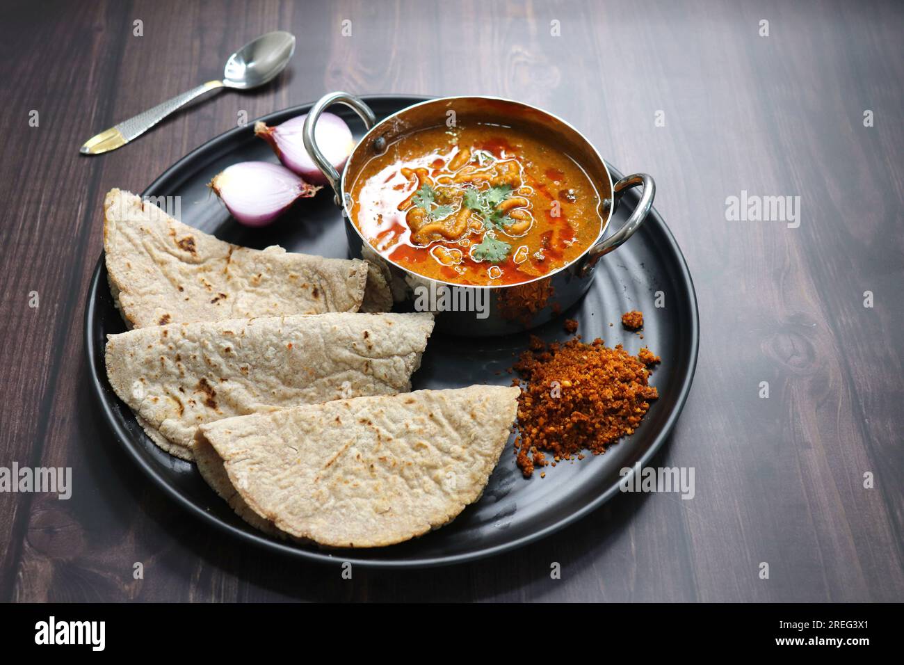 Tradizionale Sev bhaji o sev tamatar nu Shaak con Jowar Bhakri. Il SEV è un vermicelli di farina grattugiato fritto croccante. Servito con cipolla tritata e limone. Foto Stock