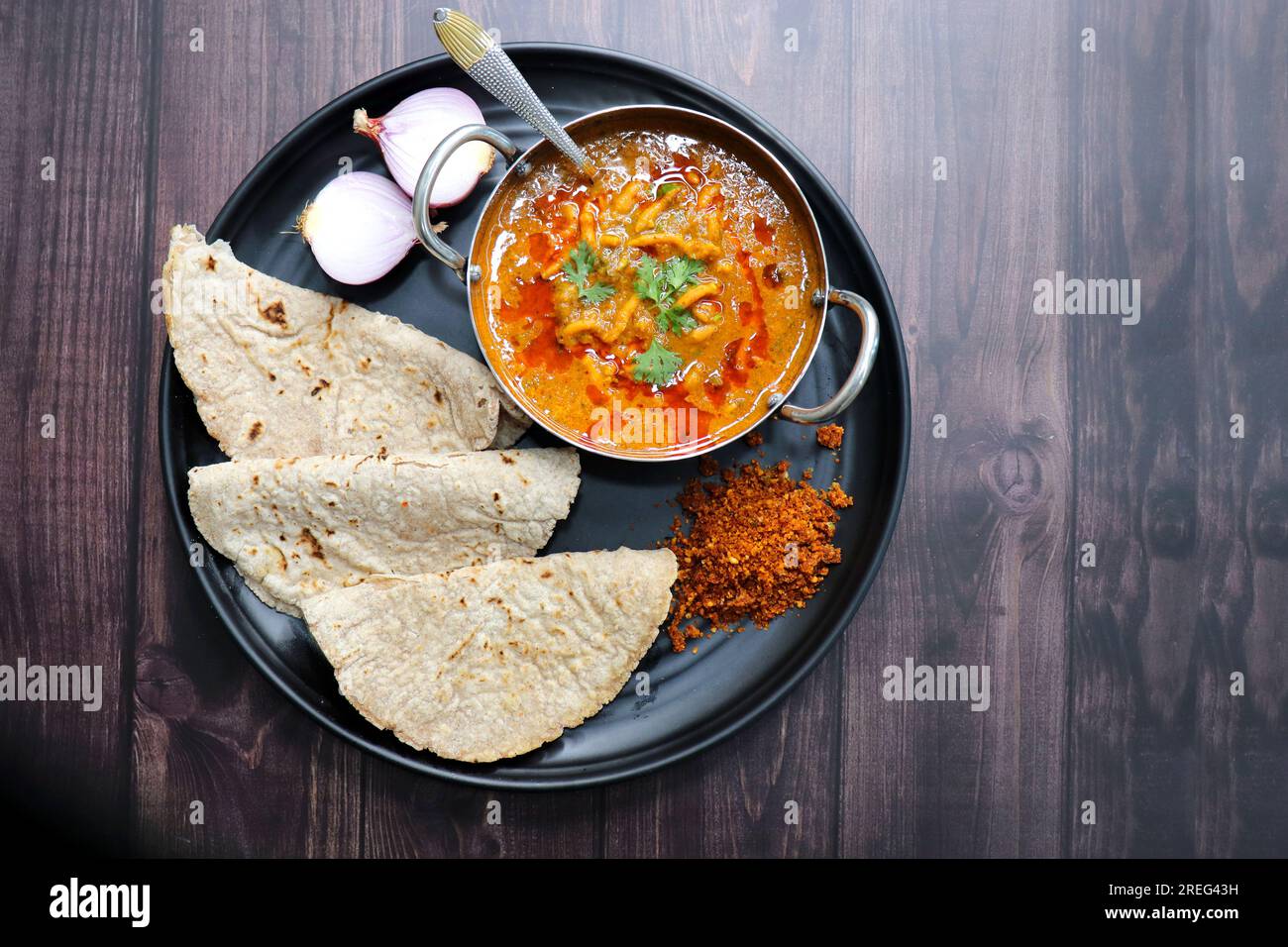 Tradizionale Sev bhaji o sev tamatar nu Shaak con Jowar Bhakri. Il SEV è un vermicelli di farina grattugiato fritto croccante. Servito con cipolla tritata e limone. Foto Stock